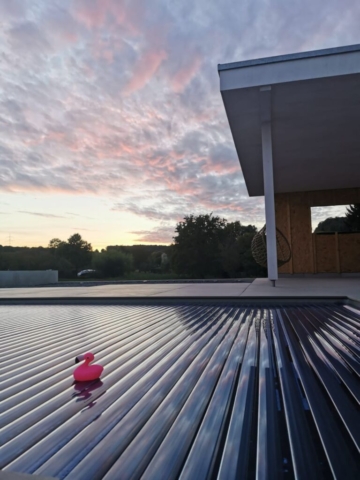 Poolabdeckung mit kleinem Gummi-Flamingo im Sonnenuntergang.