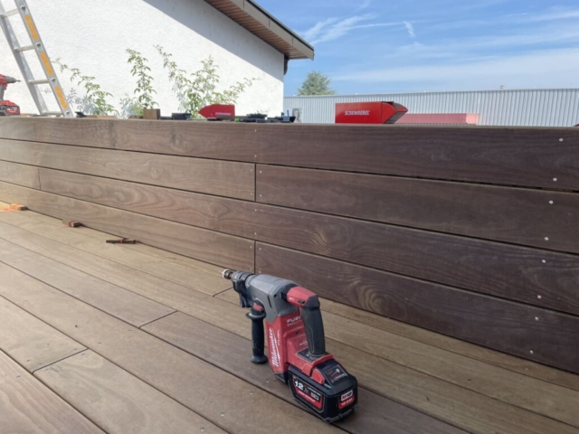 Terrasse und Pflanztröge mit Holzverkleidung. Im Vordergrund ein Akkuschrauber.