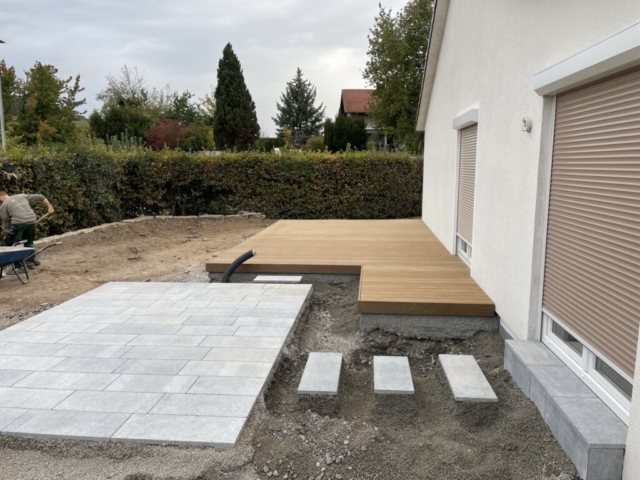 Zwei Terrassenvarinaten im Bau - eine Holzterrasse udn eine Terrasse mit Keramikplatten, zu der Stufen aus Keramikplatten aus dem Haus führen.